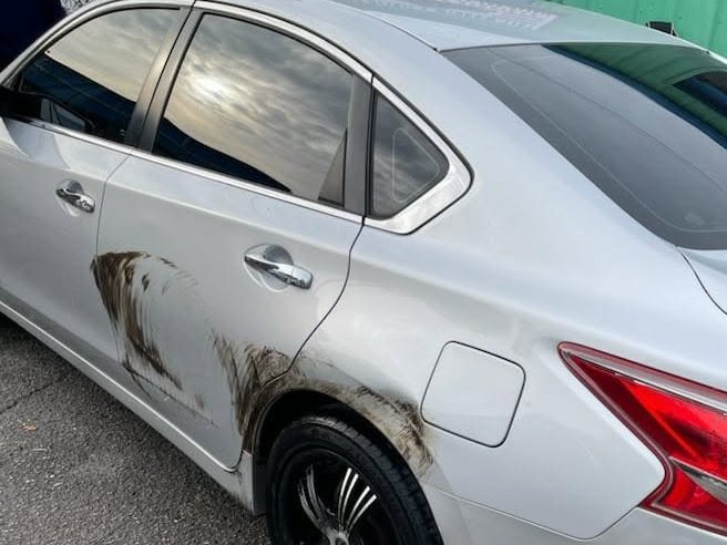 Silver sedan with dark scuff marks on the rear door and quarter panel